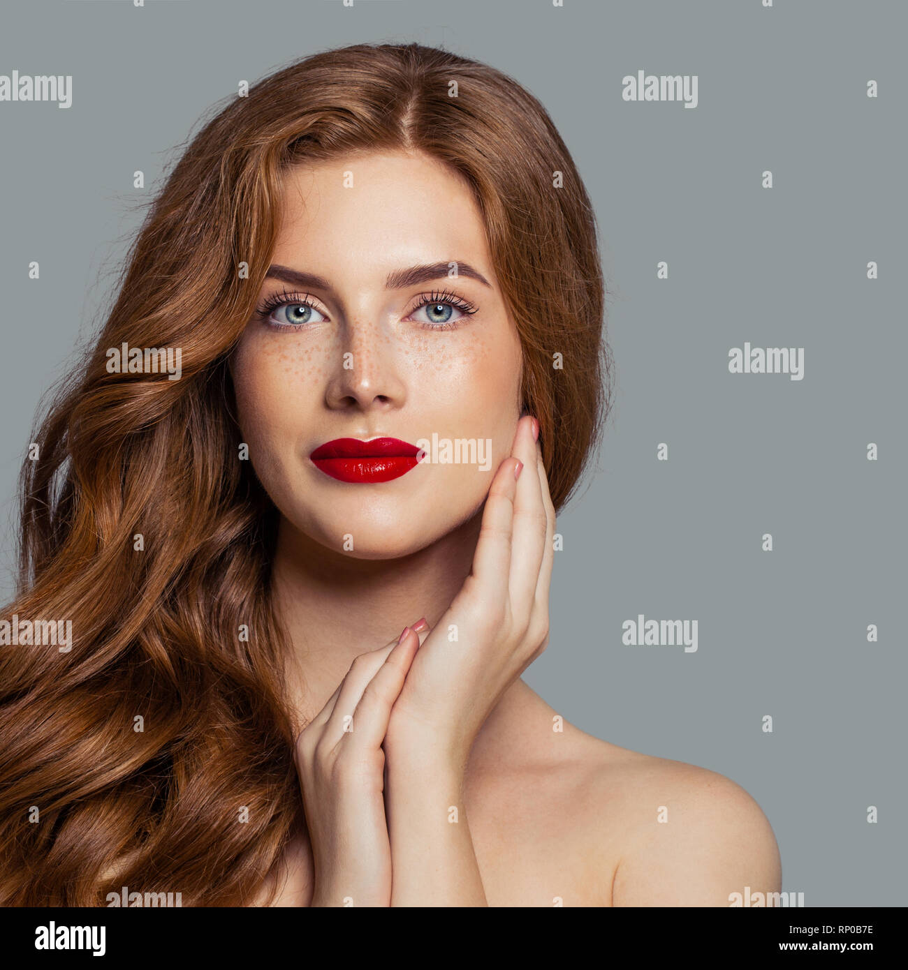 Attractive redhead girl with red lips makeup looking at camera, perfect face closeup Stock Photo