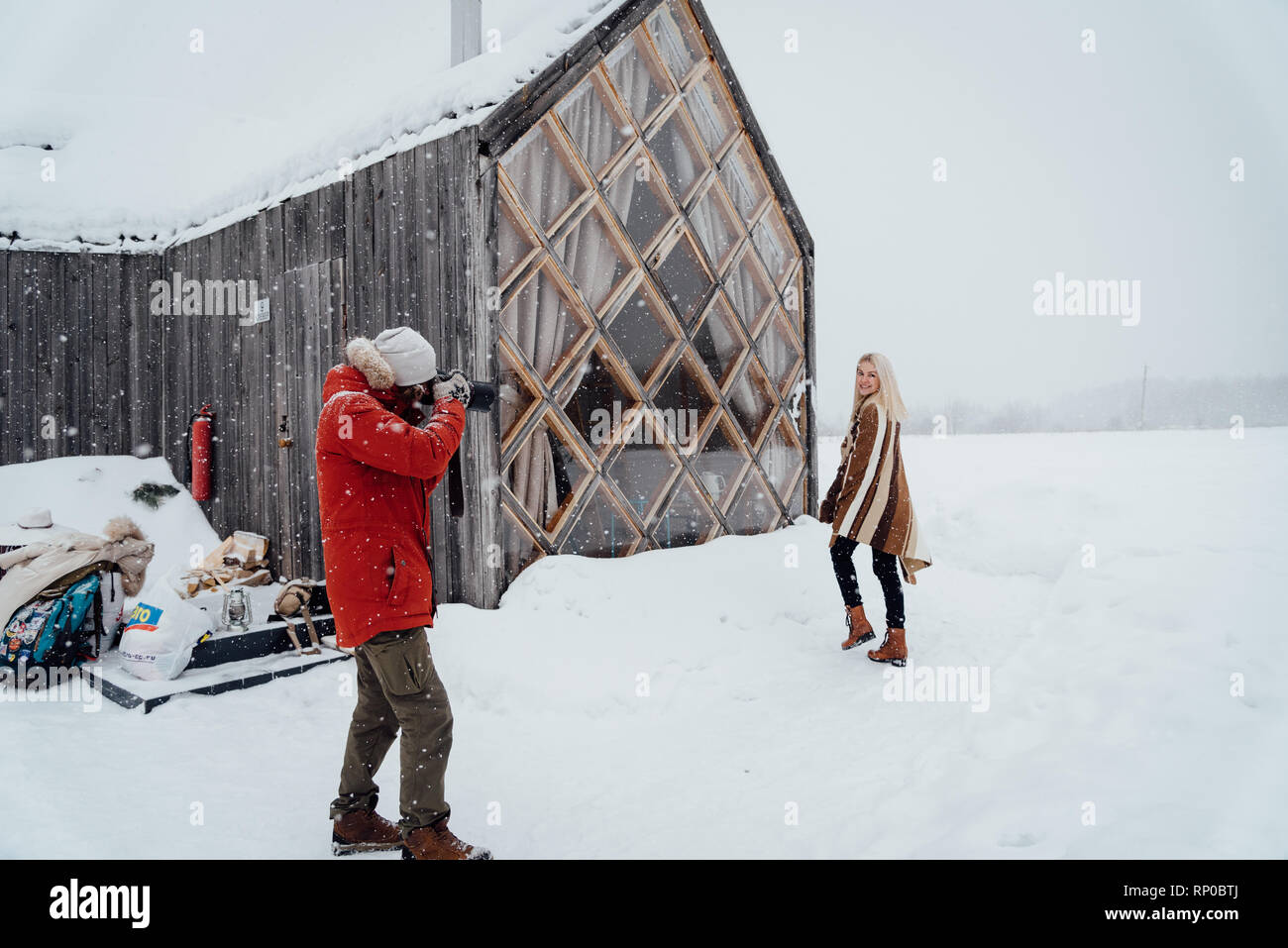 Nikola-Lenivets, Russia - January 26, 2019: A photographer takes a model in the winter near the house Stock Photo