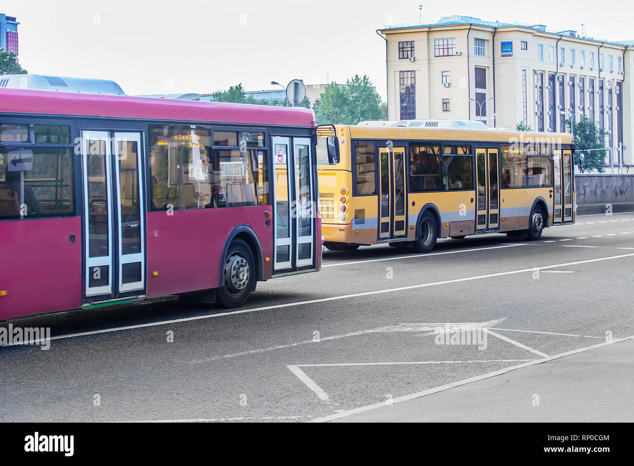 two buses go on city street in summer Stock Photo