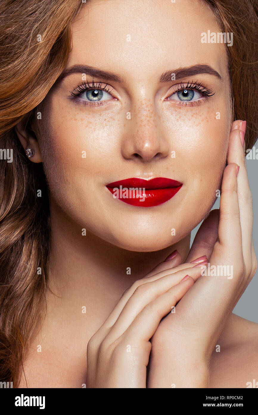 Redhead woman face closeup portrait. Ginger hair, freckles, red lips makeup and red nails Stock Photo