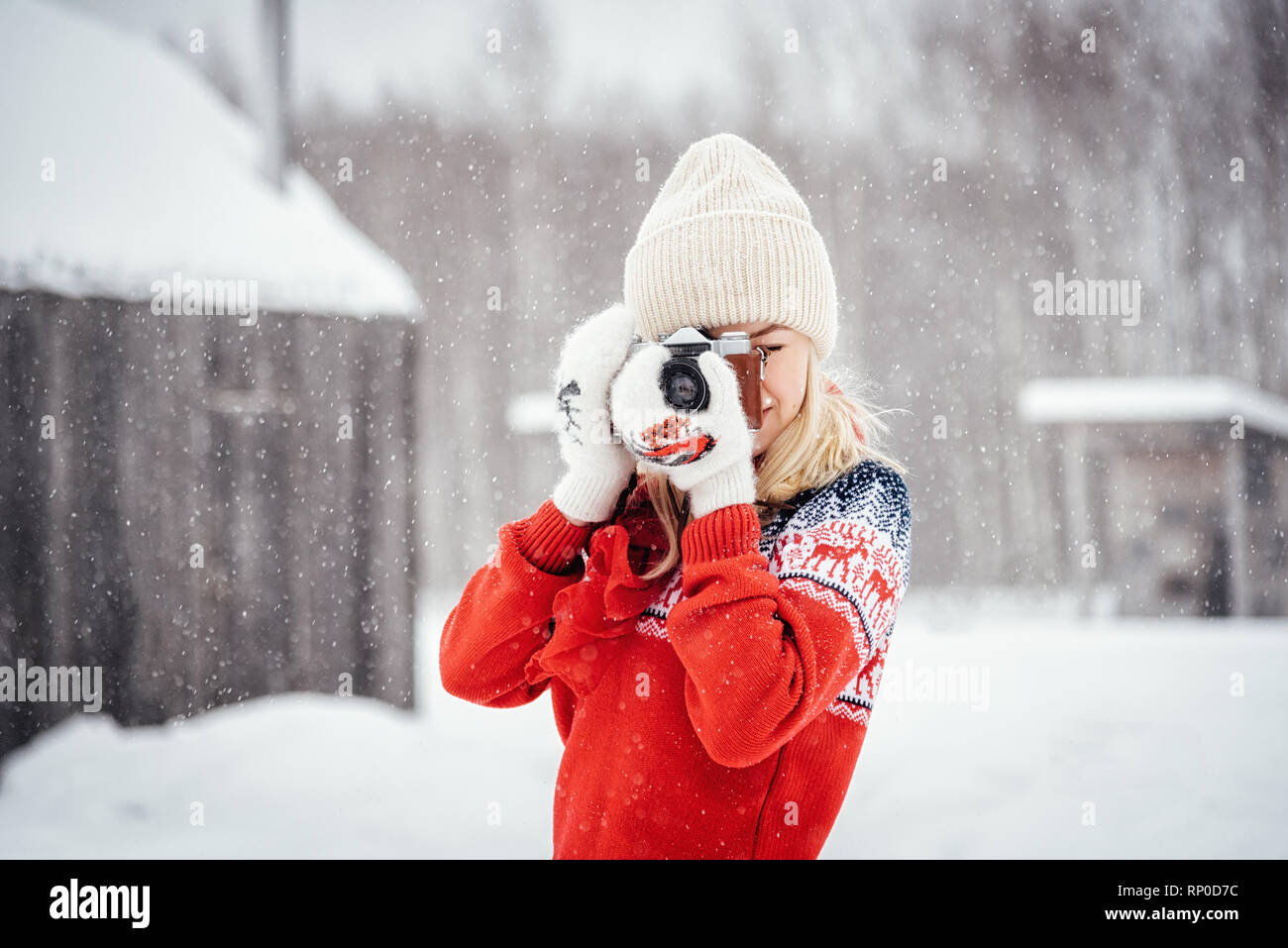 Nikola-Lenivets, Russia - January 26, 2019: Beautiful girl in a red sweater with a vintage camera Stock Photo