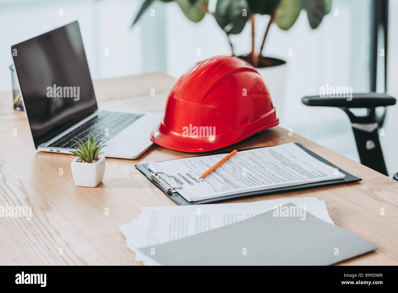 clipboard with compensation claim form and red helmet on office desk