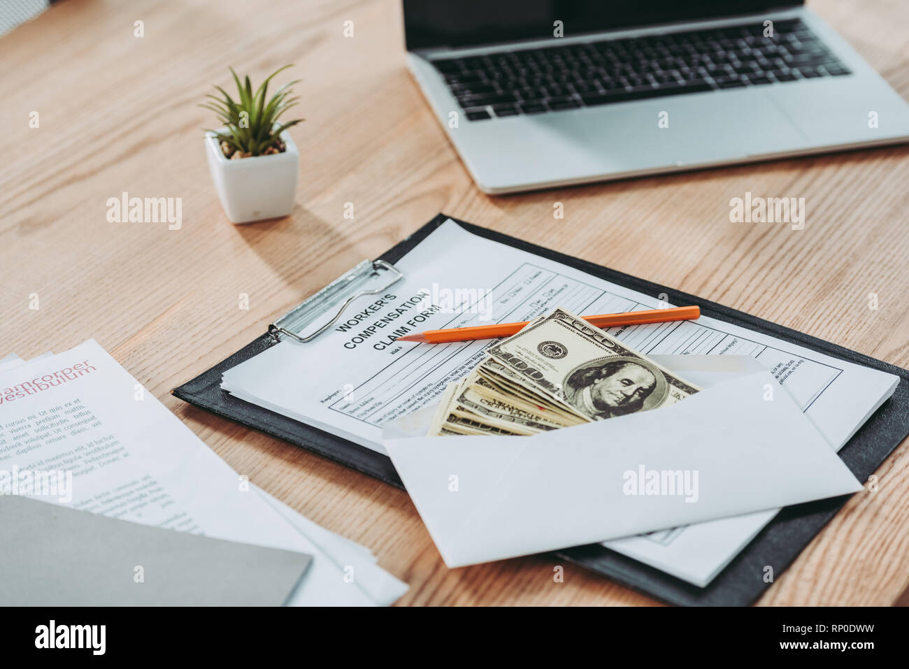 clipboard with compensation claim form and open envelope with money