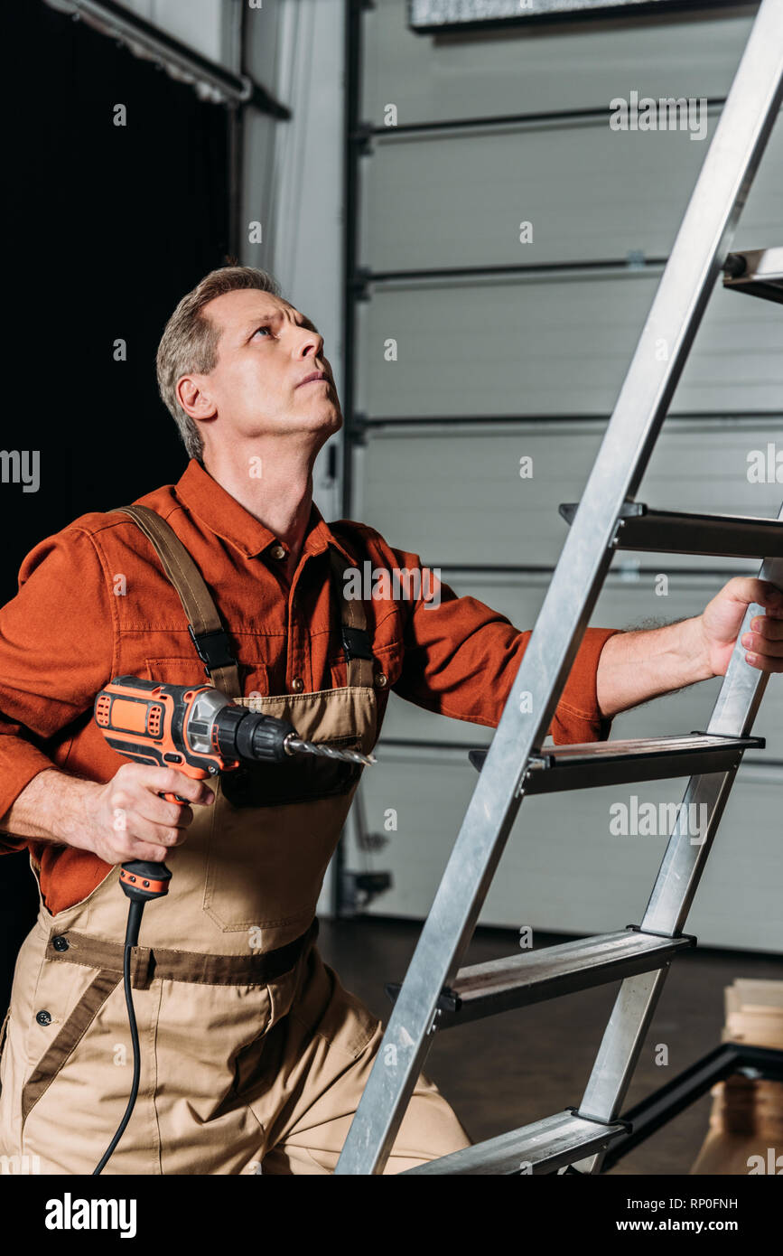 Repairman In Orange Uniform Climbing With Screwdriver On Ladder In