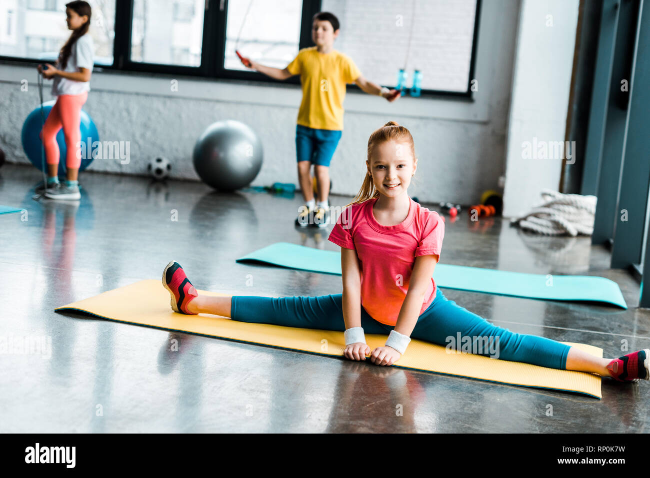 Excited kid doing twine on yellow fitness mat Stock Photo Alamy