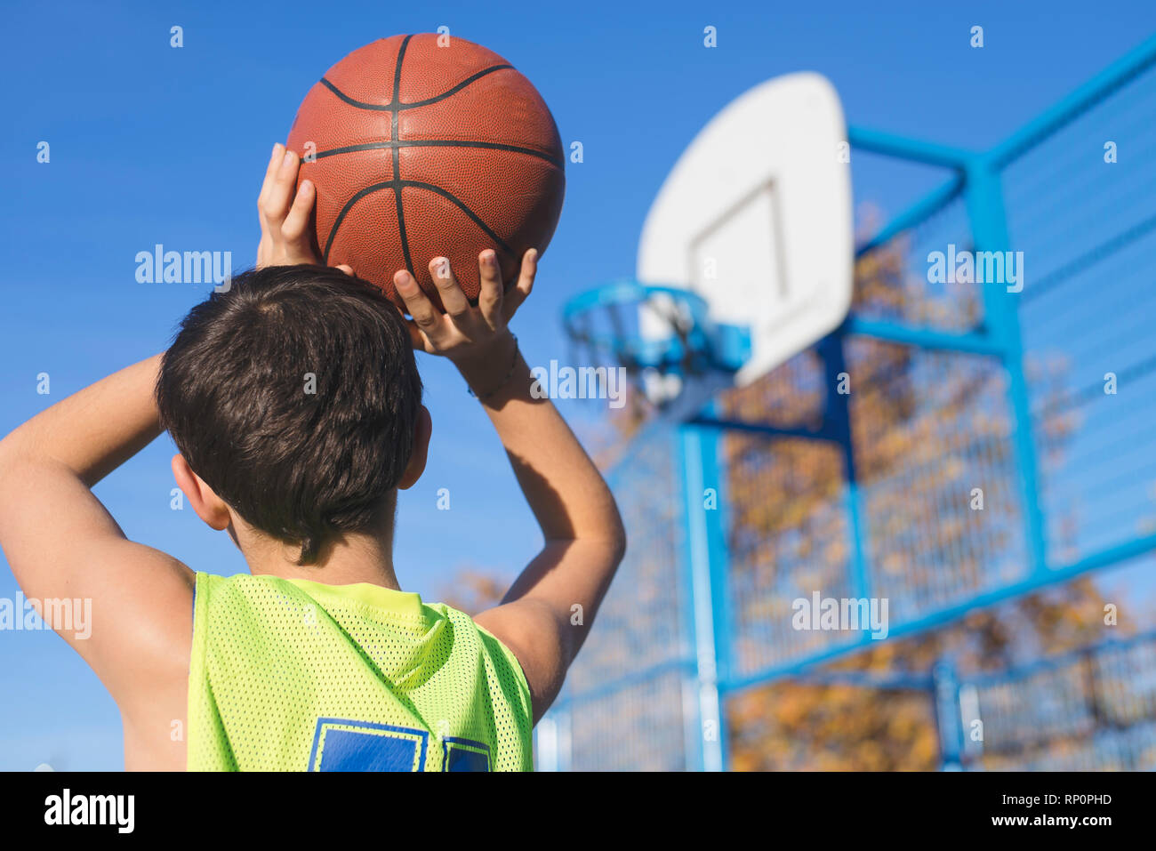 teenager throwing a basketball into the hoop from behind Stock Photo