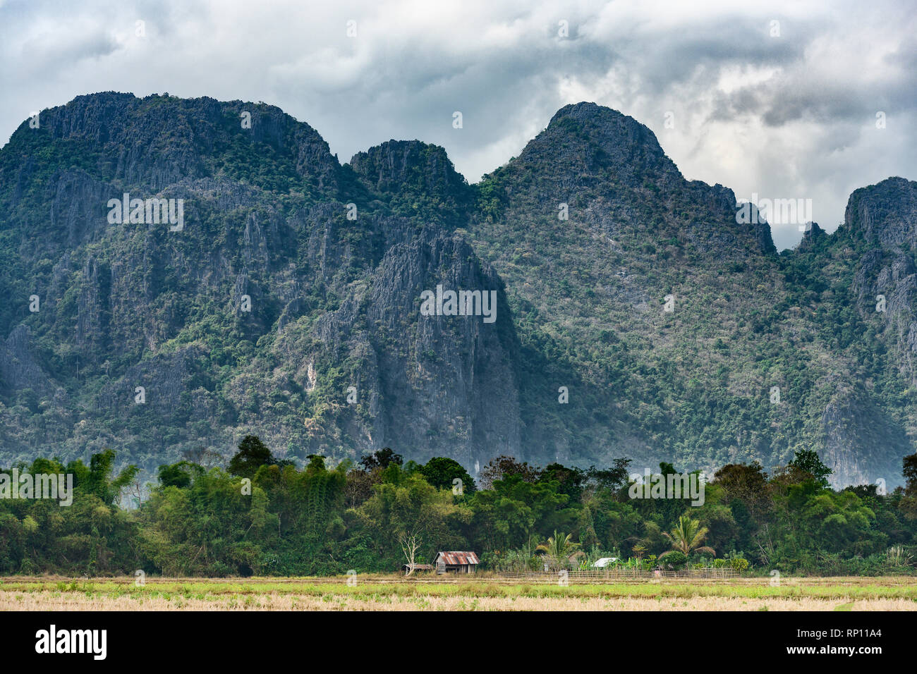 Stunning view of a some limestone mountains illuminated by some sun rays that filter through some clouds. Vang Vieng, Laos. Stock Photo