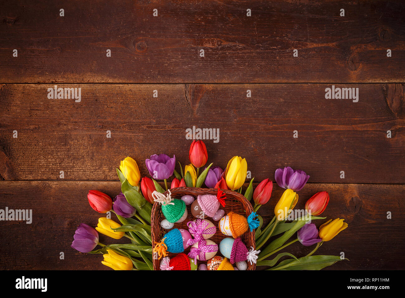 Easter greeting card with eggs and tulips on wooden background. Top view with space for your greetings Stock Photo
