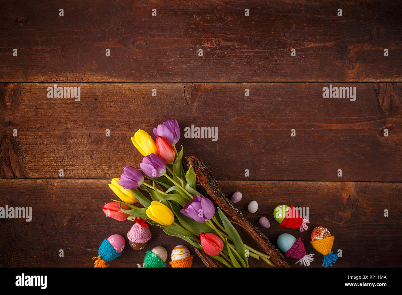 Easter composition with tulips and Easter eggs with little hats on wooden planks Stock Photo