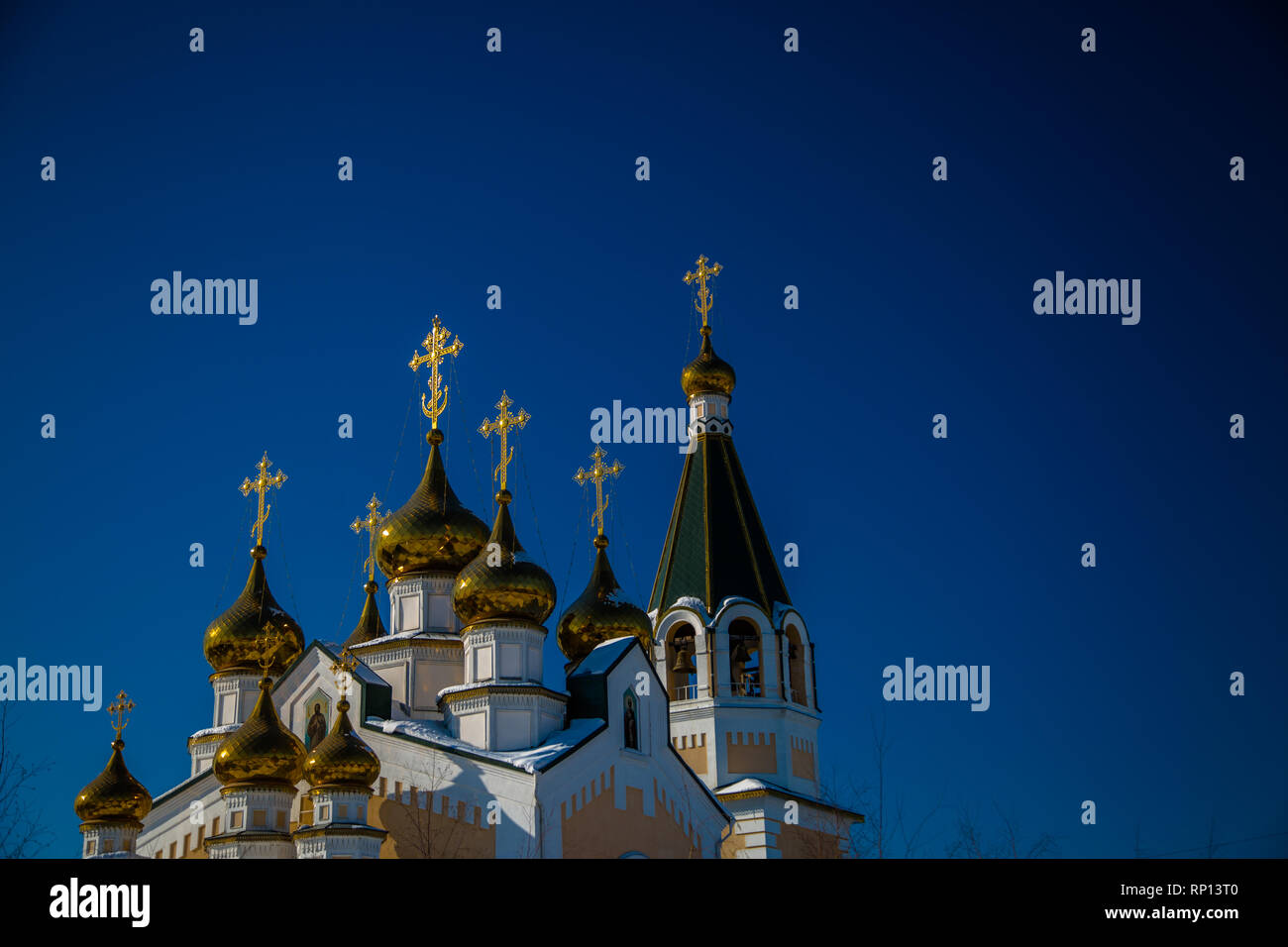The crosses and onion domes of Russian Orthodox Church set against a blue sky. Stock Photo