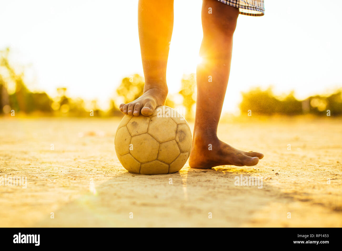 sport outdoor picture of kids having fun playing soccer football for exercise under the twilight sunset sky. Stock Photo