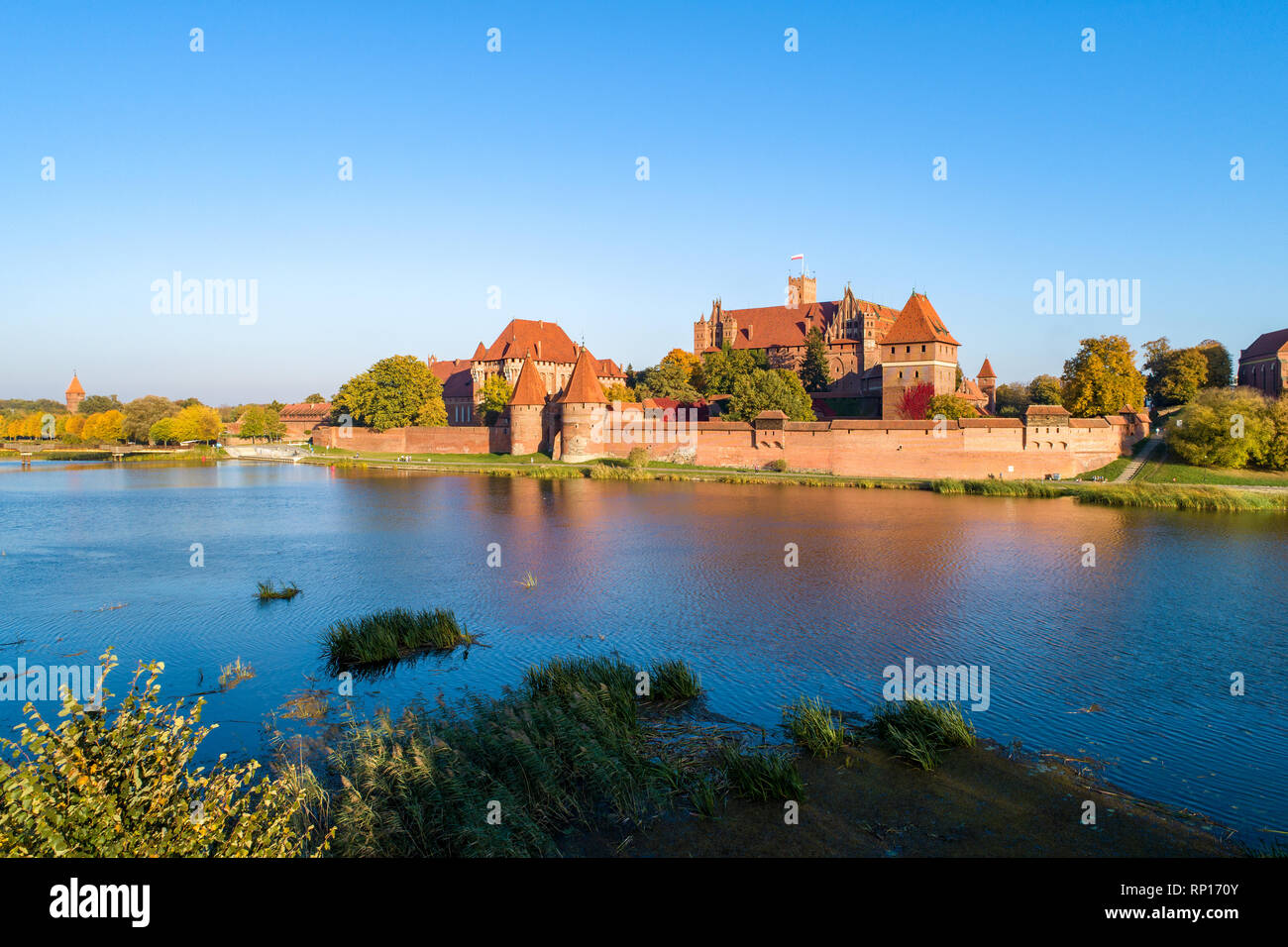Medieval Malbork (Marienburg) Castle in Poland, main fortress of the Teutonic Knights at the Nogat river. Aerial view in fall in sunset light. Stock Photo