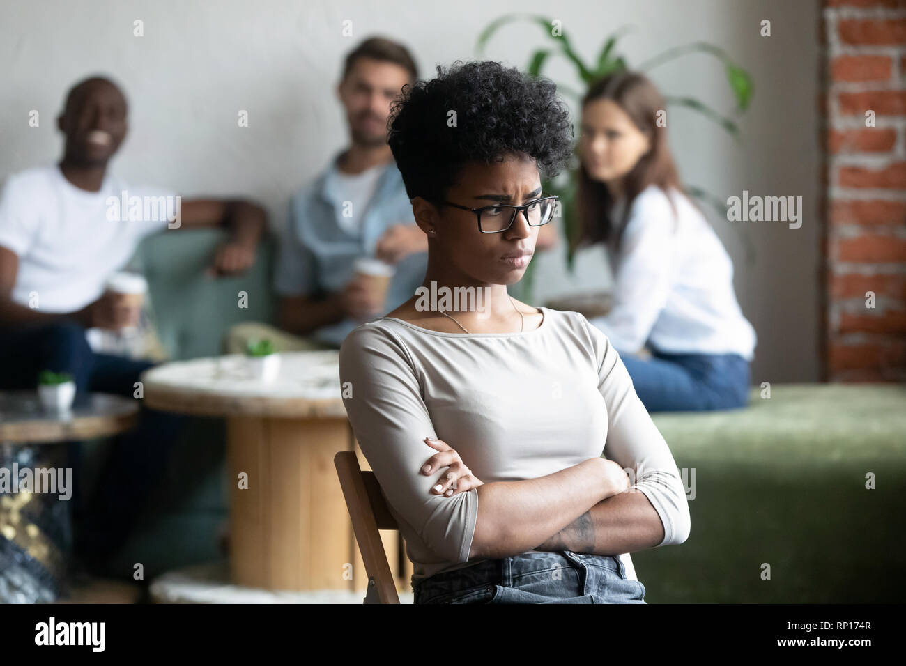 Black girl outcast sitting apart from peers in cafeteria Stock Photo
