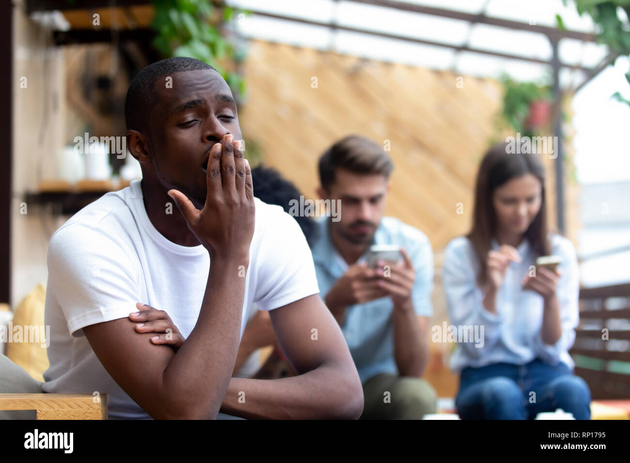 Diverse friends sitting in cafe focus on bored black guy Stock Photo