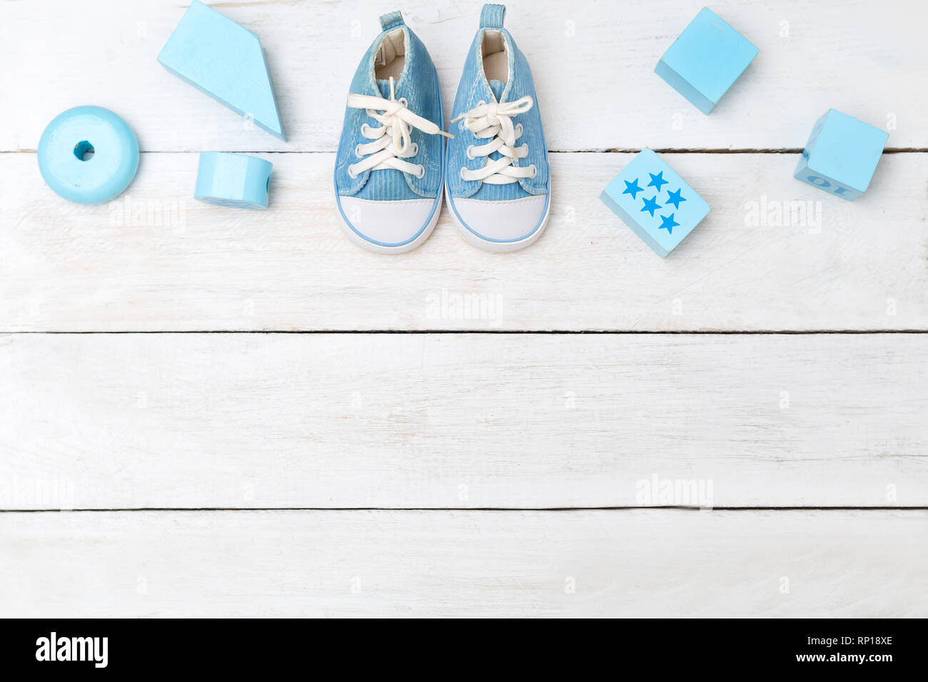 baby boy blue shoes and wooden toys on a white wooden background. View from above Stock Photo