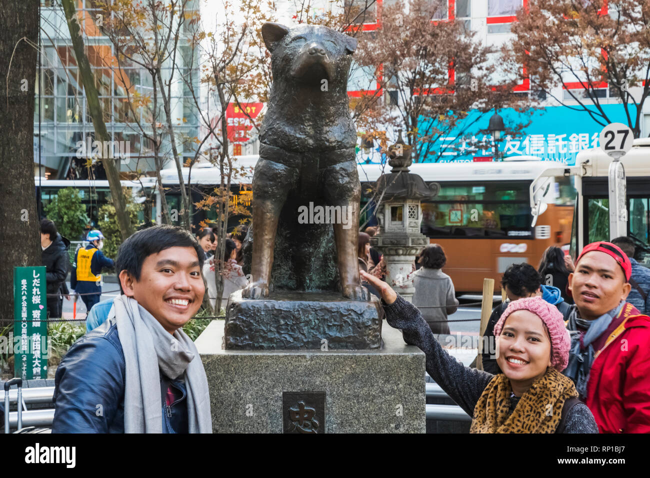 Japan, Honshu, Tokyo, Shibuya, Asian Tourists Posing with Hachiko Statue Stock Photo