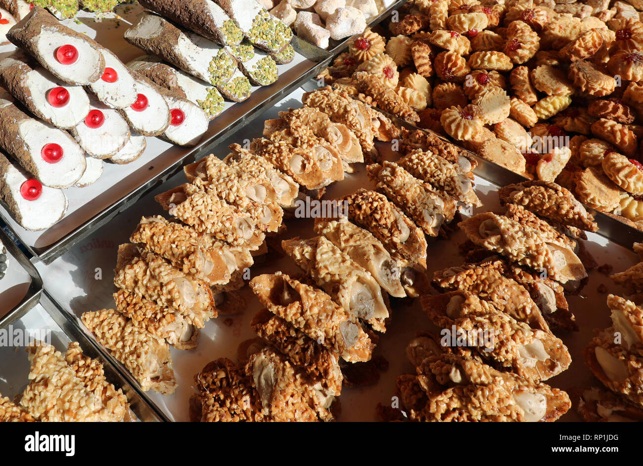 many pastries with pistachio and cherries for sale in the Italian pastry stand called Cannolo Siciliano Stock Photo