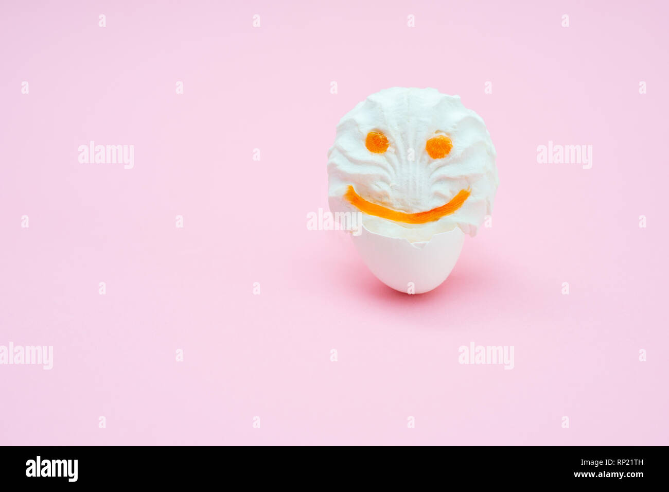 marshmallows fluff with eyes and smiles from carrots. Funny face in an egg-shell on a pink background. isolated Stock Photo