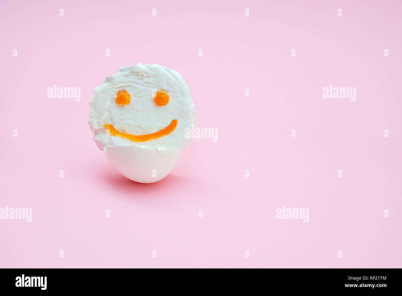 marshmallows fluff with eyes and smiles from carrots. Funny face in an egg-shell on a pink background. isolated Stock Photo