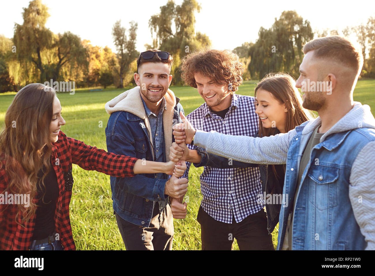 Group of friends connected thumb up in the park. Stock Photo