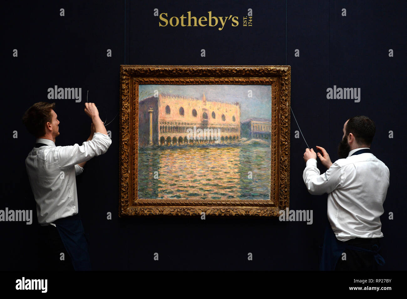 Gallery assistants adjust Le Palais Ducal by Claude during a
