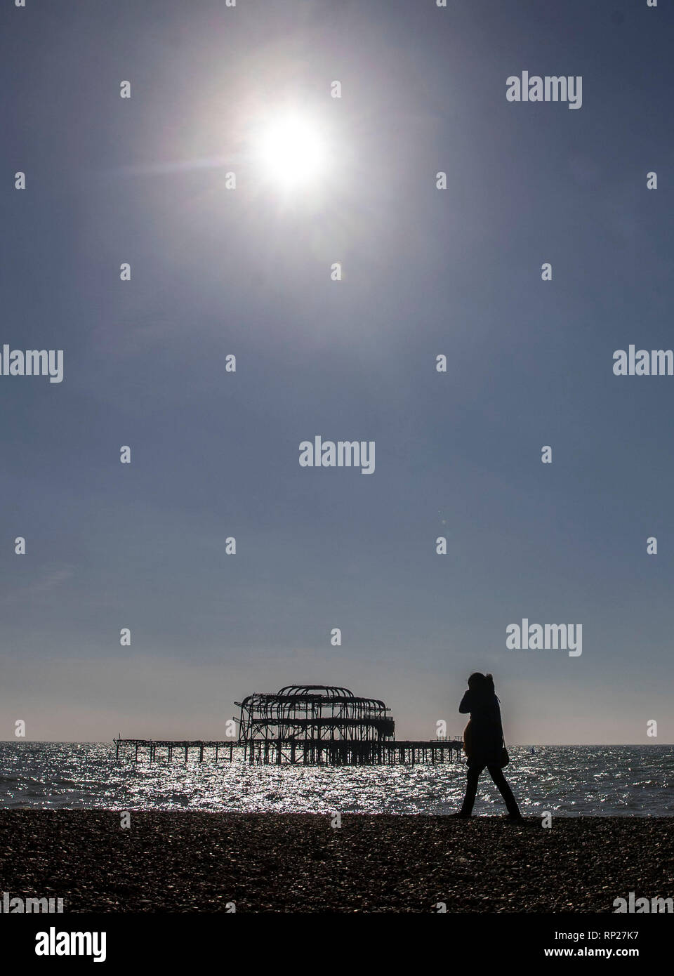 A woman passes the old pier in Brighton, Sussex. Stock Photo