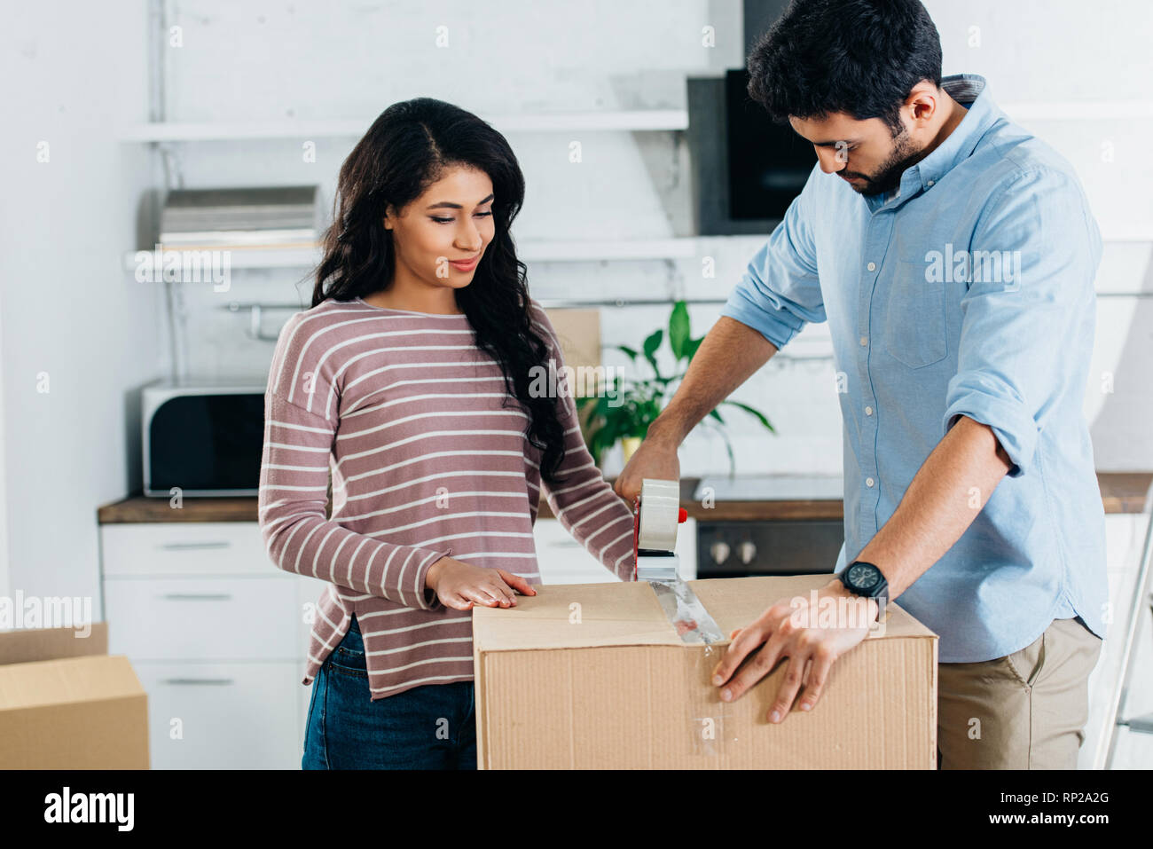 happy latin couple packing boxes while moving to new home Stock Photo ...