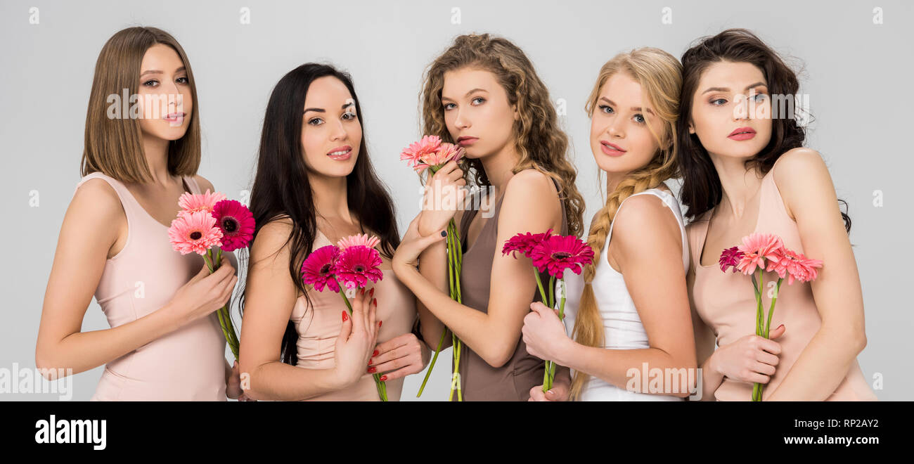 beautiful female friends holding pink flowers and standing isolated on ...