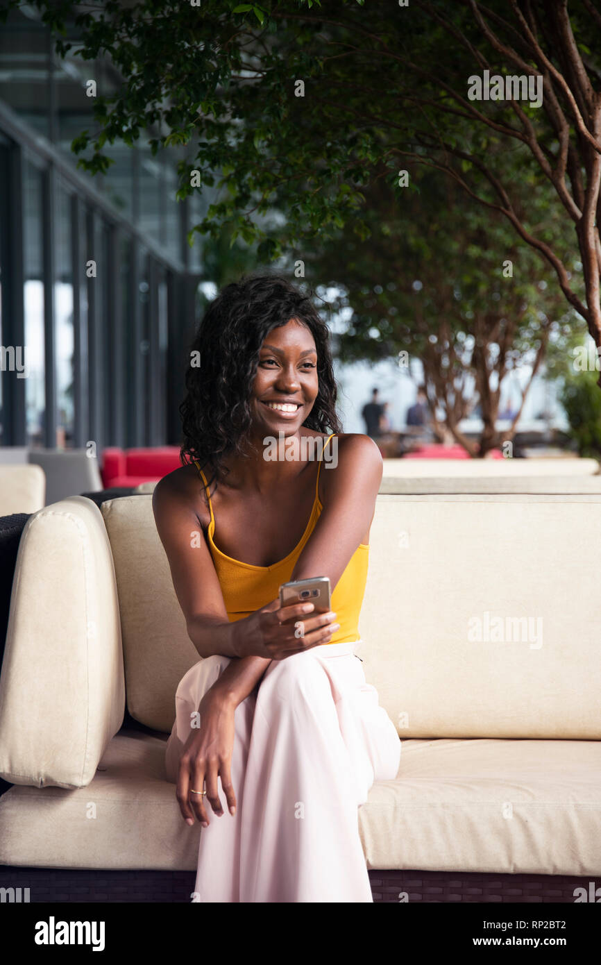 An attractive, stylish African Brazilian woman sitting on a lounge chair Stock Photo