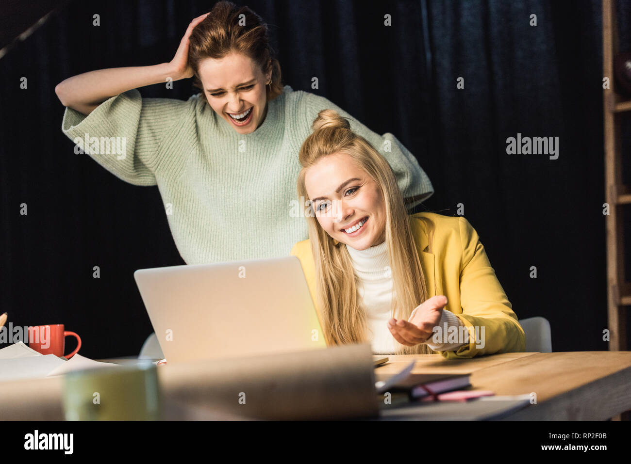 beautiful female it specialists laughing while using laptop in office Stock Photo