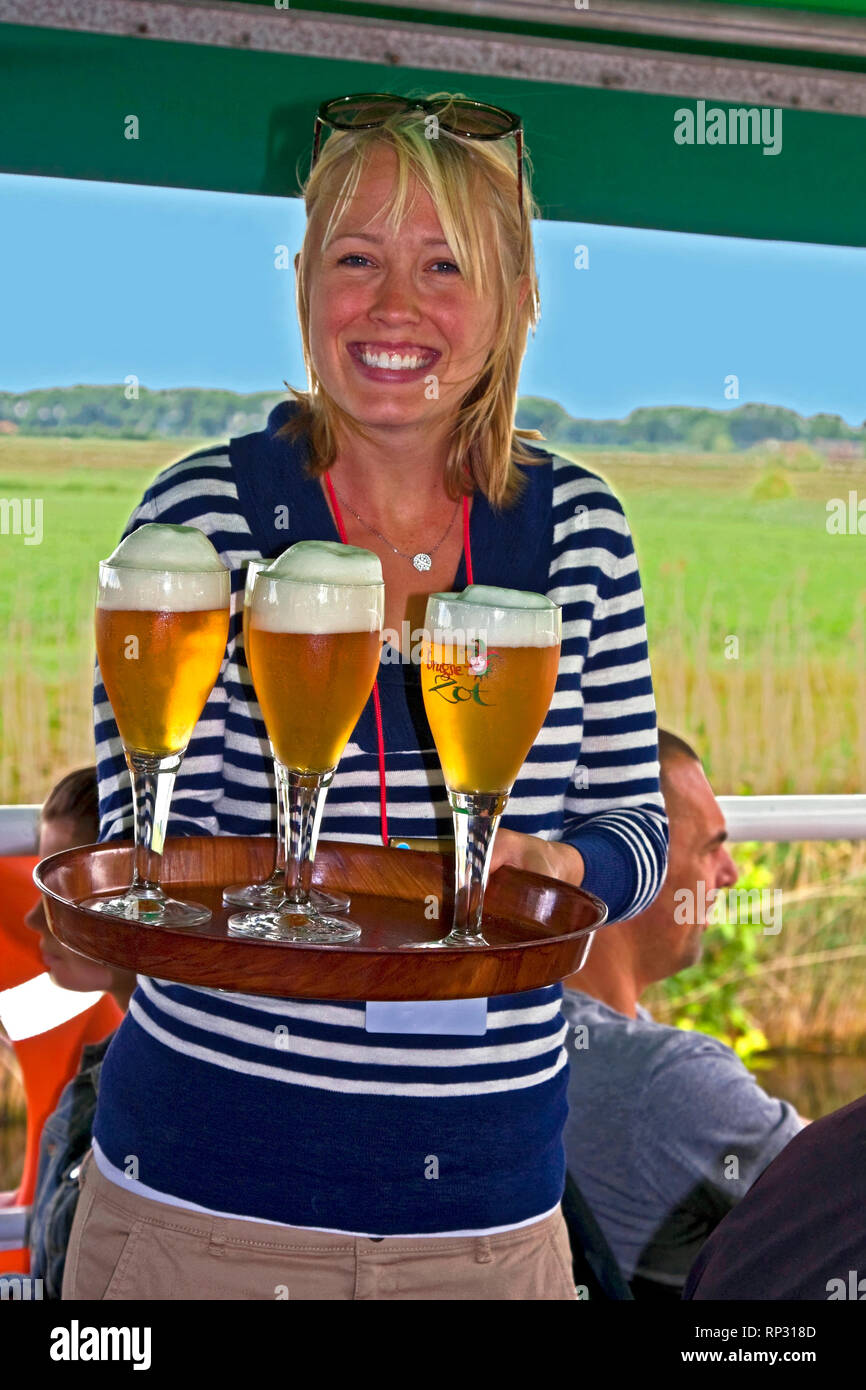young woman serving beer; stemmed glasses; foam; canal boat; waitress; job; happy; smiling; Europe, Bruges, Belgium, MR; vertical Stock Photo