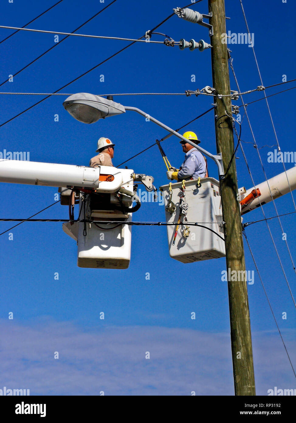 2 linemen, cutting electric wires; bucket trucks; occupation; work; job