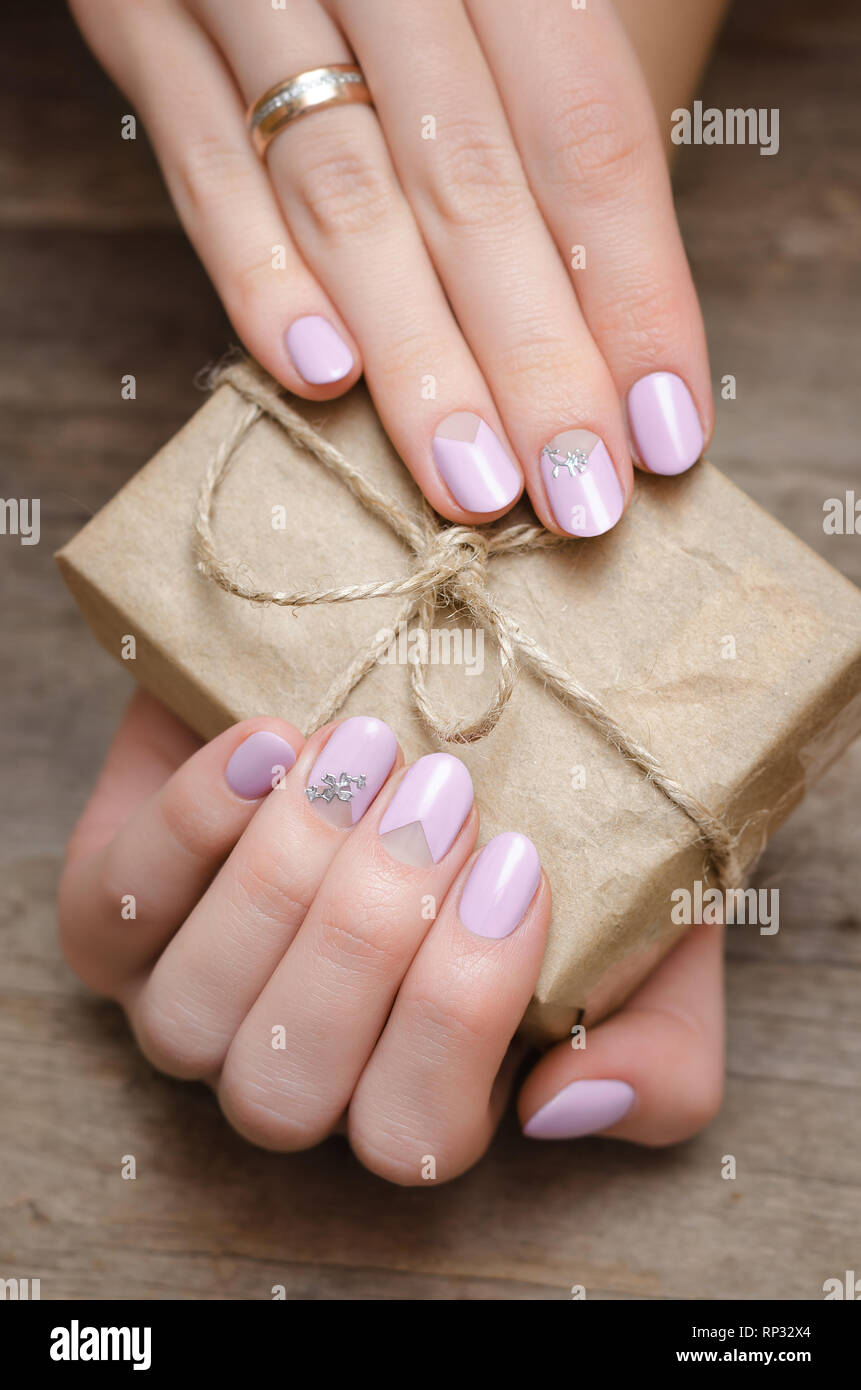 Female hands with light pink nail design holding a present box ...