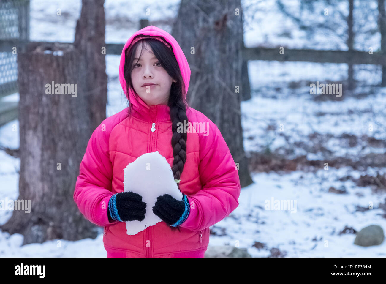 Young Asian Girl with pink jacket with hood holding ice Stock Photo