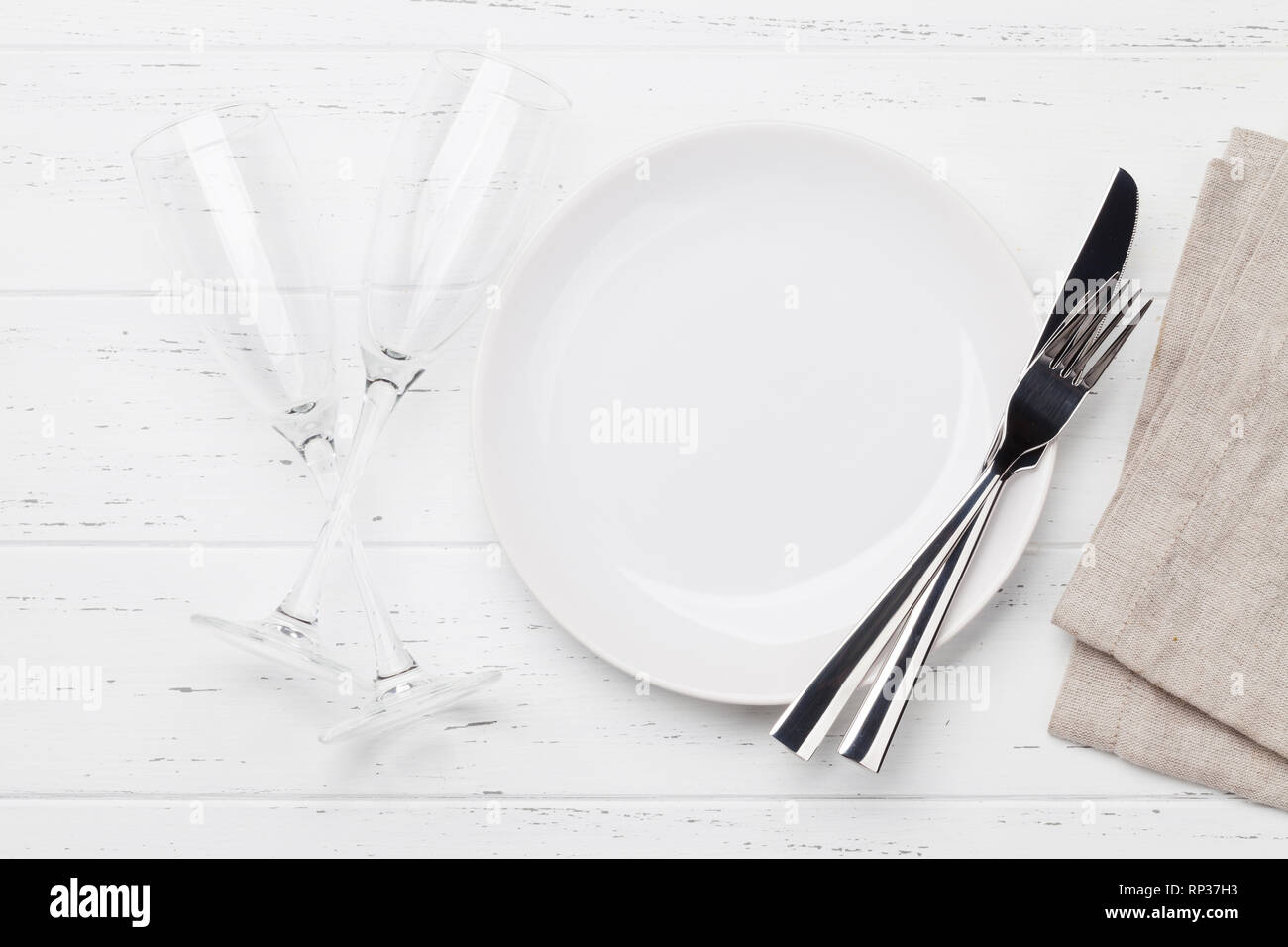 Table setting. Empty plate, knife, fork and champagne glasses. Top view