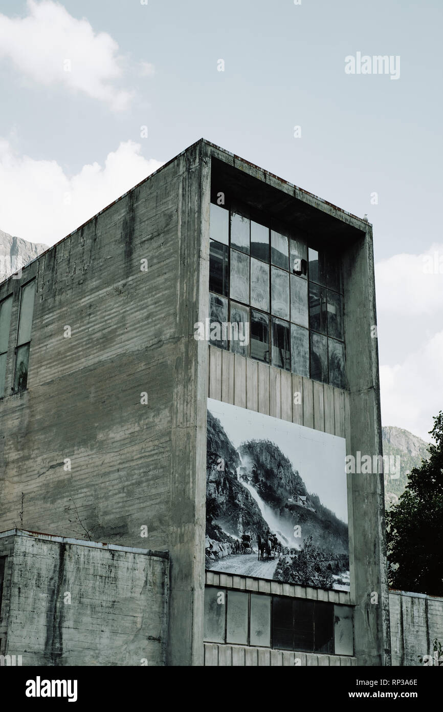Empty abandoned industrial concrete building in Odda Roldal Norway with a large b/w historical print of the same location. Stock Photo