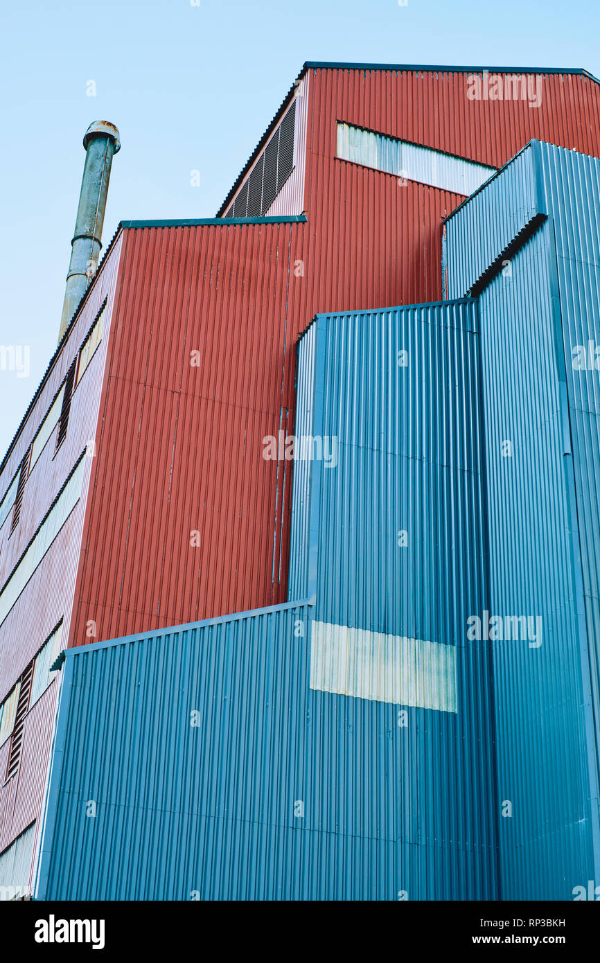 A blue and red corrugated metal clad industrial building abstract detail. Stock Photo