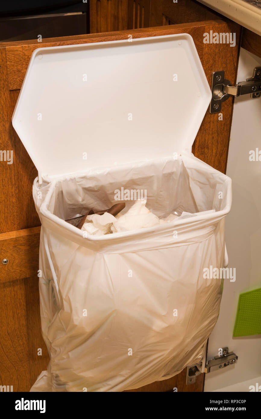 Trash bag on an opened kitchen cabinet door Stock Photo