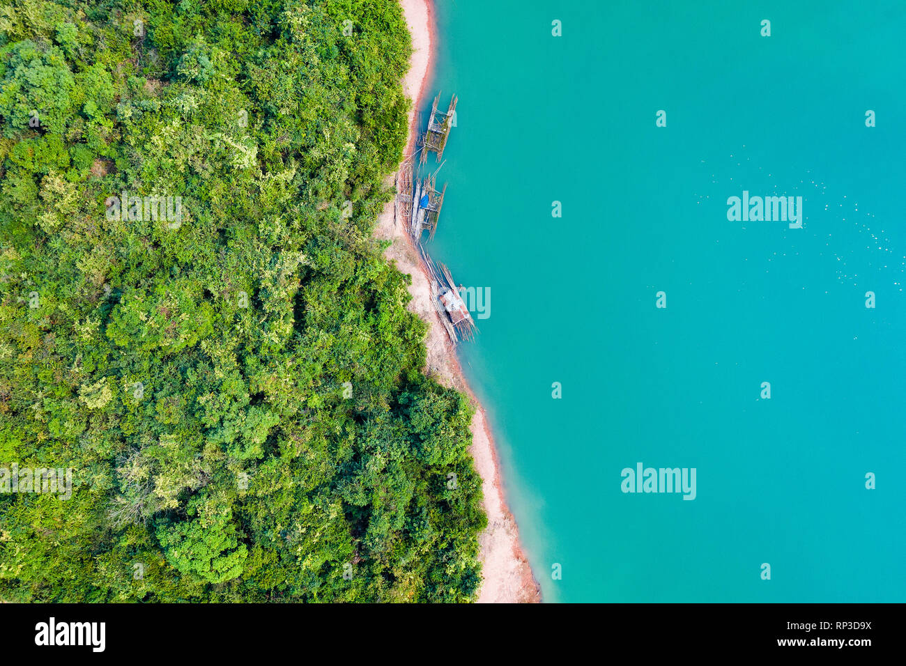 (View from above) Stunning aerial view of a a green coast of a tropical island with some traditional fishing boats in Nam Ngum Reservoir. Stock Photo