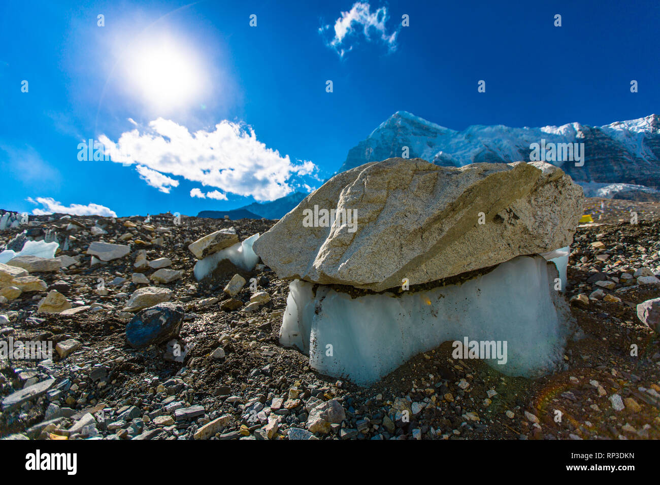 Large boulders balance on melting ice as the season changes from winter to summer. Stock Photo