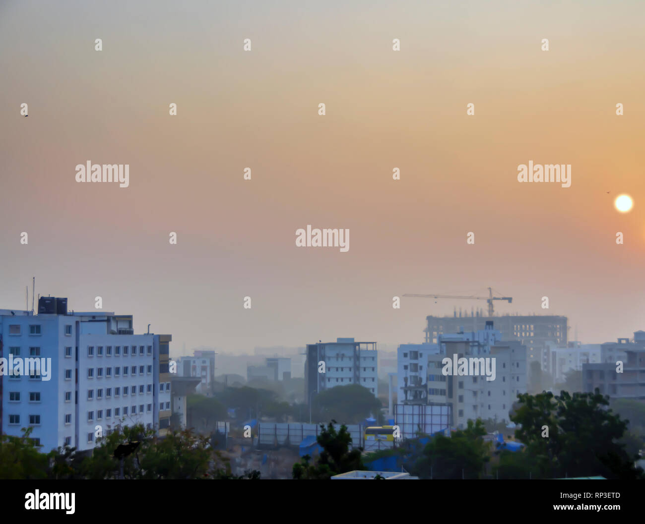 Sun rising in Kondapur and HITEC city, Hyderabad, Telangana, India. The landscape is covered under early morning mist and smog, late January. Stock Photo