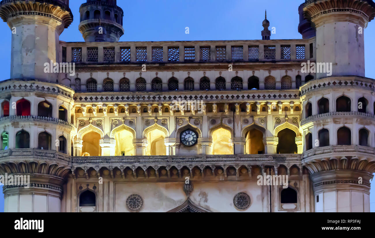 A closeup of the facade and the clock of Charminar, 'four minarets', at dusk. The interiors of the monument in Hyderabad, India, is lit up by lights. Stock Photo