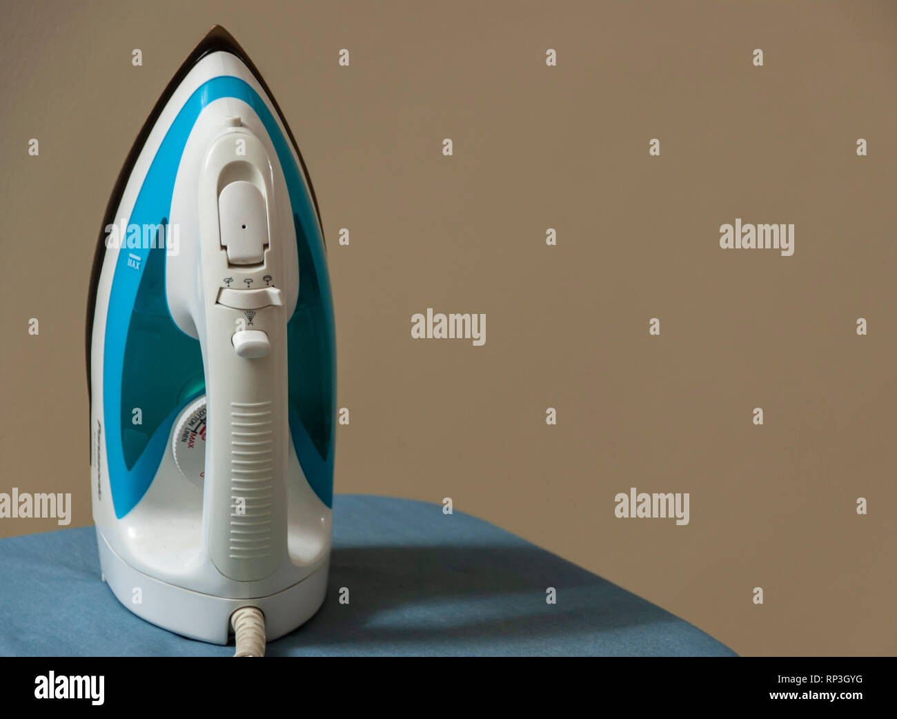 An iron resting on an ironing table. Stock Photo