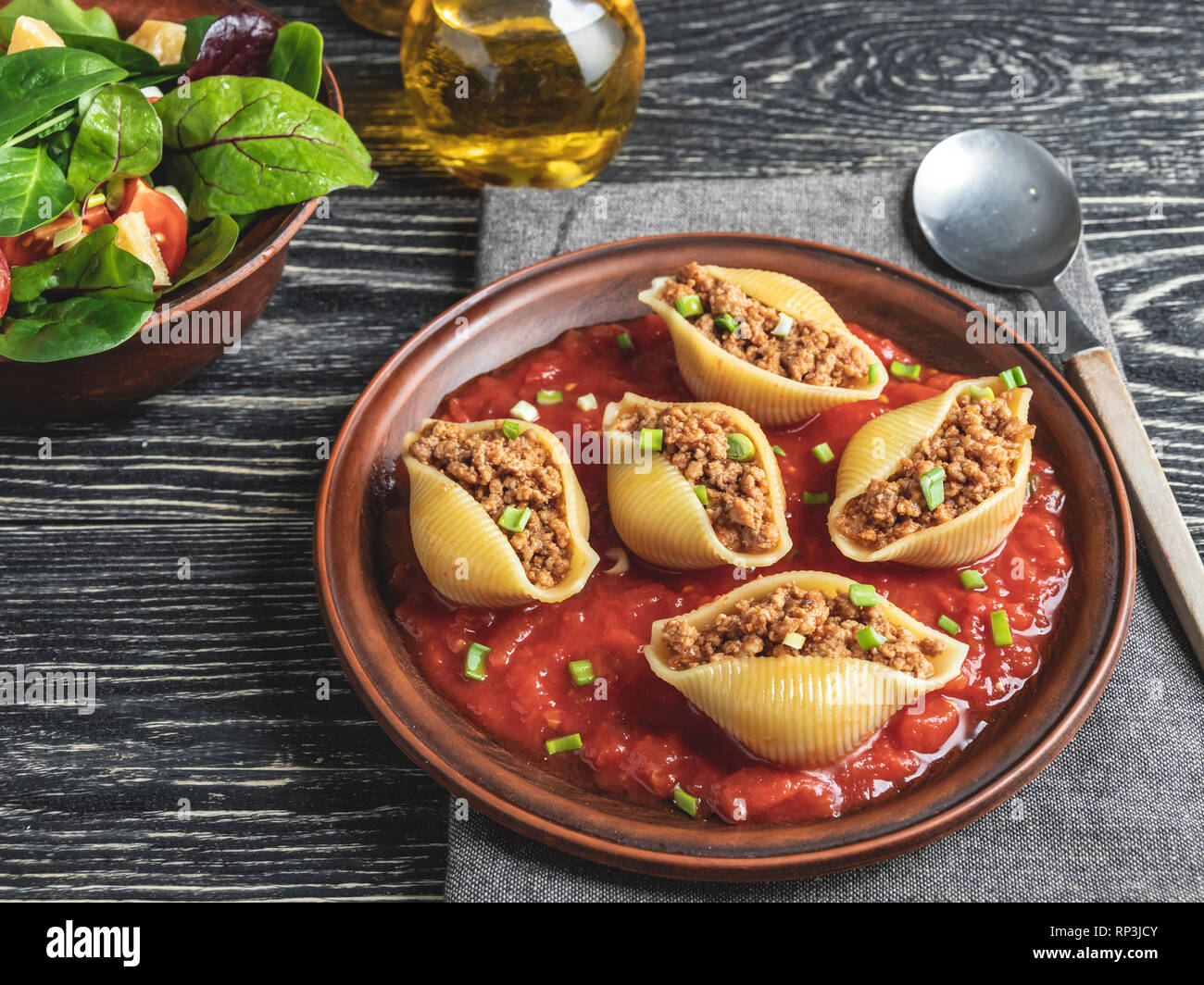 cooked pasta conchiglioni stuffed minced meat, tomato sauce on plate Stock Photo