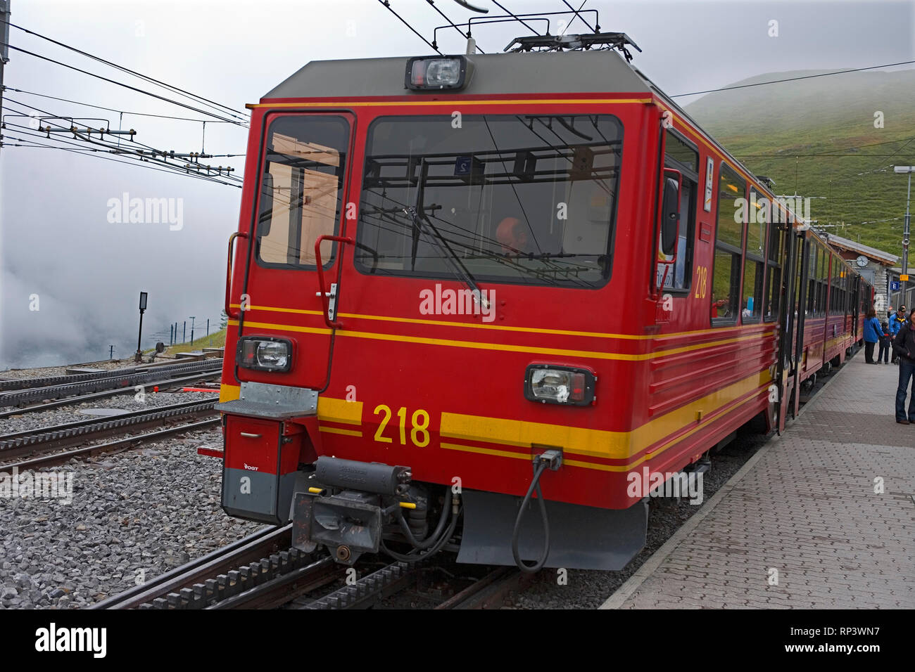 Jungfraubahn (JB) train in mist at Kleine Scheidegg station, Bernese Oberland, Switzerland Stock Photo