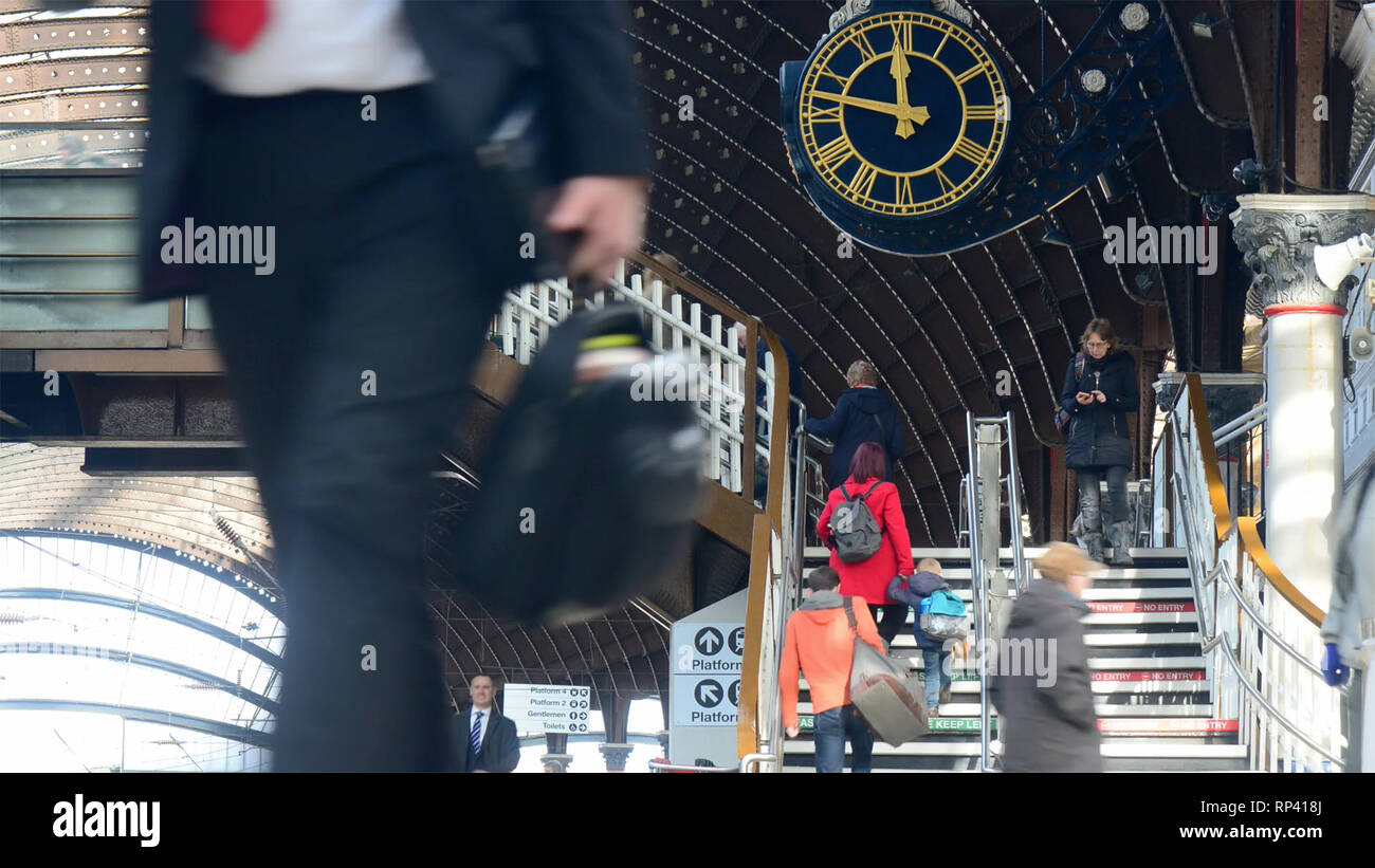 businessman passing station clock rushing to catch train at york railway station united kingdom Stock Photo