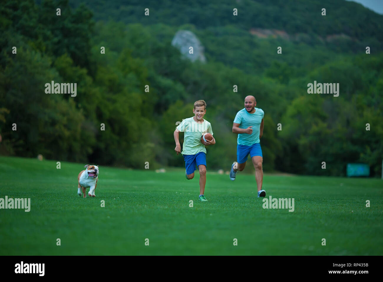 father-and-son-are-running-in-park-with-dog-english-bulldog-father-s