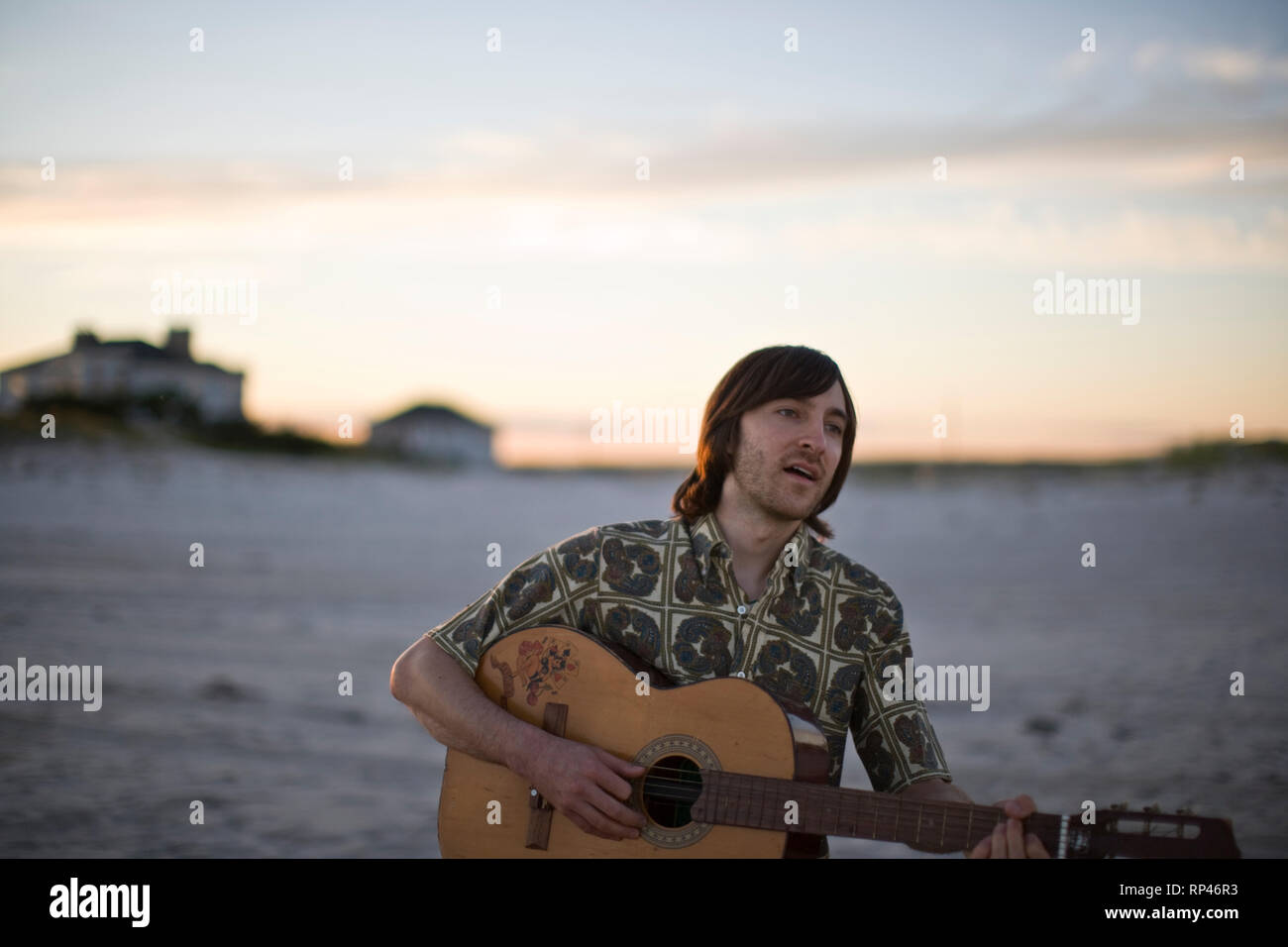 Young man playing a guitar on a beach. Stock Photo