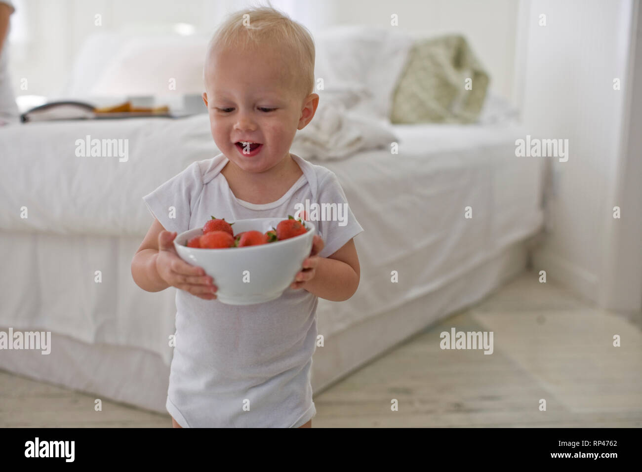 Small toddler carrying a bowl of strawberries Stock Photo Alamy