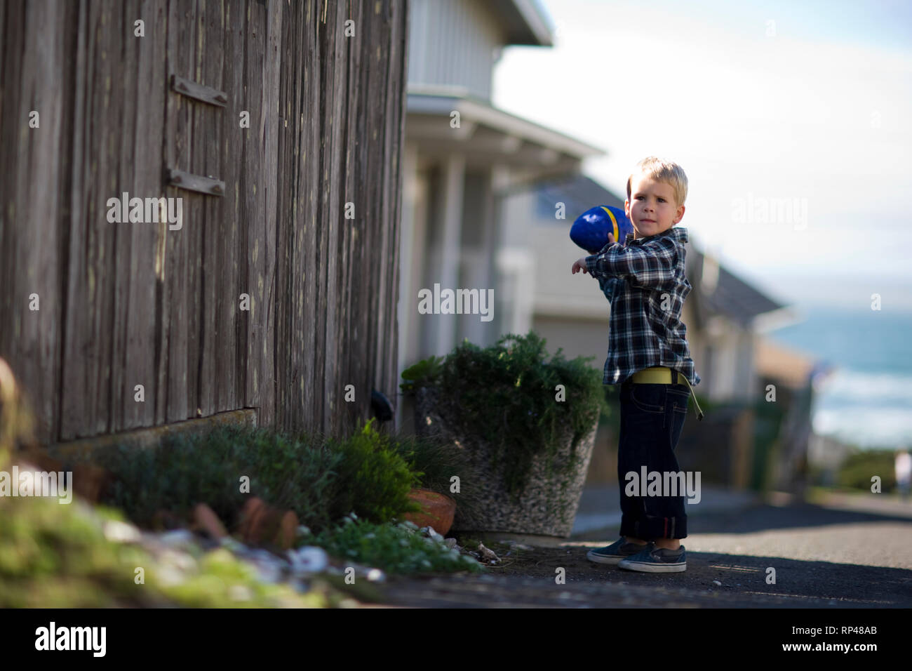 Portrait of a young boy playing outside with a toy football. Stock Photo